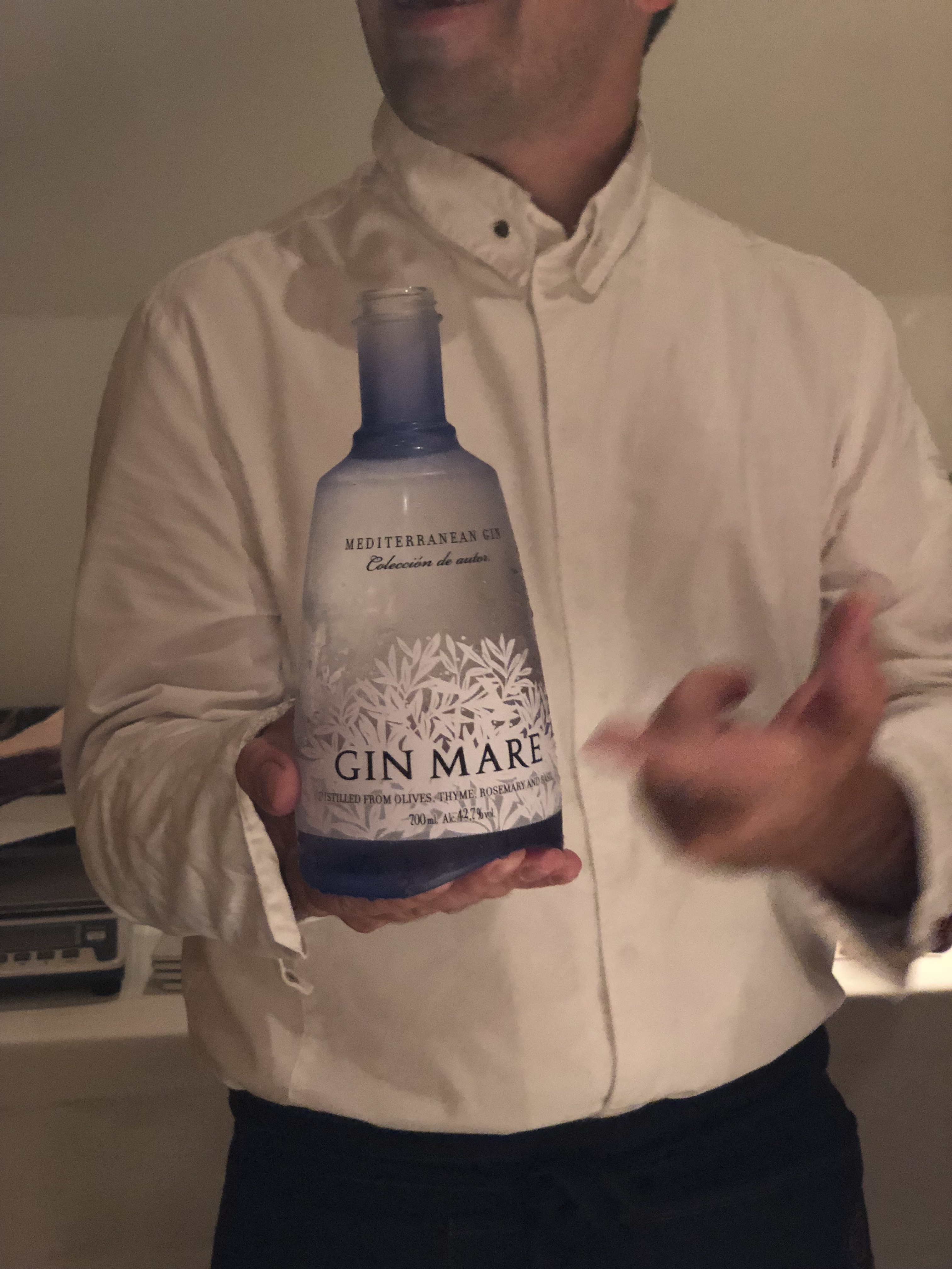 A chef holding a bottle of premium Gin Mare