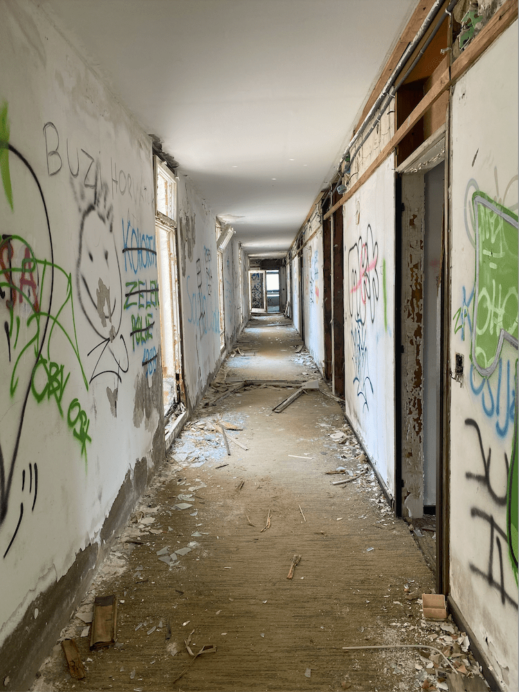 Hallway littered with graffiti, broken glass, and wood paneling.